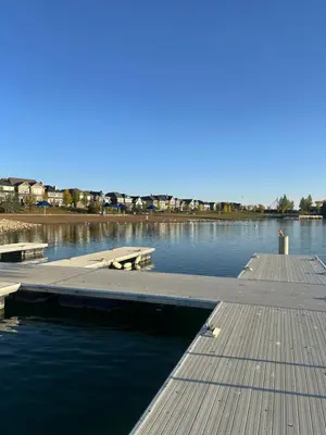 a dock on a body of water with two benches at Sunny Queen-size Bedroom with Private Bath in Brand New House in Calgary
