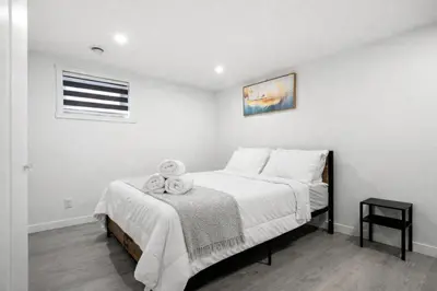 a bedroom with a bed with white sheets and a window at Bright 5-Bed Retreat Near the Zoo and Downtown in Calgary