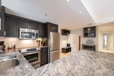 a kitchen with black cabinets and stainless steel appliances at Woodrun Lodge 108 by Outpost Whistler in Whistler