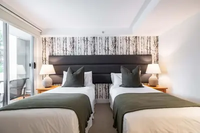 two beds in a room with two lamps at Woodrun Lodge 108 by Outpost Whistler in Whistler