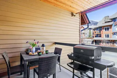 a patio with a grill and a table and chairs at Exciting Rockies 1BR Escape with Hot Tub, Pool and BBQ in Canmore