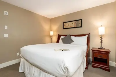 a bedroom with a large white bed with a book on it at Mountain Bliss Spacious 2BR with Pool and Hot Tub in Canmore
