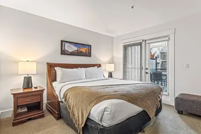a bedroom with a large bed and a window at Mountain View 2BR Condo with Hot Tub, Pool and Gym in Canmore