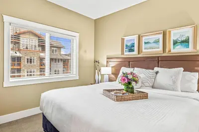 a bedroom with a large bed and a window at Cozy 2BR Retreat Mountain View with Pool and Hot Tub in Canmore
