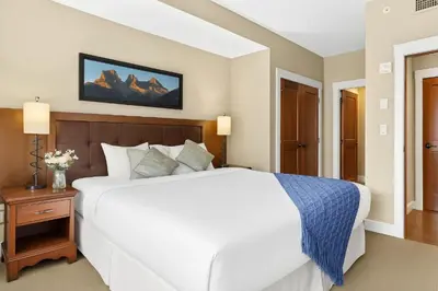 a bedroom with a large white bed and a night stand at Spacious Rockies Escape near Banff Hot tub and Gym in Canmore