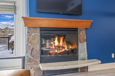 a fireplace with a tv on a blue wall at Spacious 2BR Oasis with Pool and Gym Close to Banff in Canmore