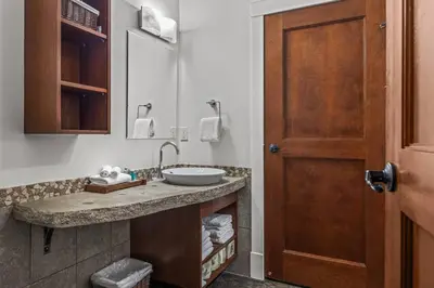 a bathroom with a sink and a wooden door at Mountain View Penthouse with Pool and Hot Tub in Canmore