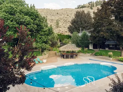 a swimming pool in a yard with a table and a grill at Similkameen Valley Resort in Cawston