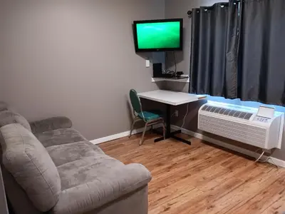 a living room with a couch and a desk and a tv at Hinton Highway Inn in Hinton