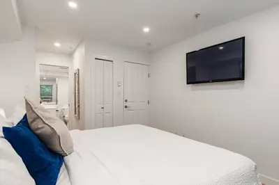a white bedroom with a large bed and a flat screen tv at Private Hot Tub | Pool | Free Parking | Sauna in Whistler
