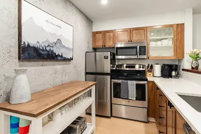 a kitchen with stainless steel appliances and wooden cabinets at Private Hot Tub | Pool | Free Parking | Sauna in Whistler