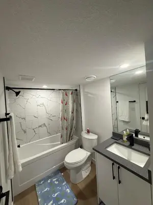 a bathroom with a tub and a toilet and a sink at Cozy 2 Bedroom Suite Close to Amenities in Edmonton