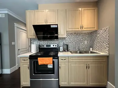 a kitchen with white cabinets and a stove and a sink at Bright & Cozy 1B1B in Vancouver-close to YVR Airport & DT, Free Parking, Private Entrance, in Vancouver