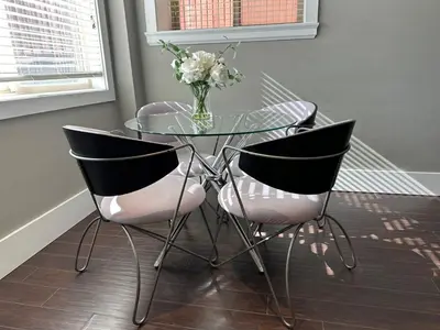 a glass table with two chairs and a vase of flowers at Bright & Cozy 1B1B in Vancouver-close to YVR Airport & DT, Free Parking, Private Entrance, in Vancouver