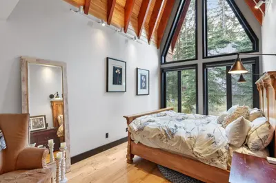 a bedroom with a bed and a large window at Luxury Whistler 6BR Chalet, Hot Tub and Music Loft in Whistler