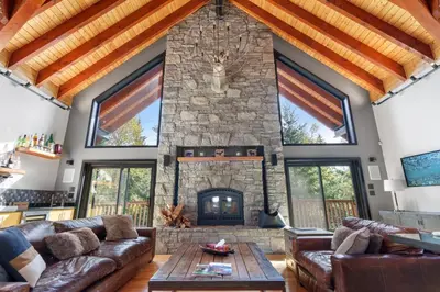 a living room with a stone fireplace and leather couches at Luxury Whistler 6BR Chalet, Hot Tub and Music Loft in Whistler