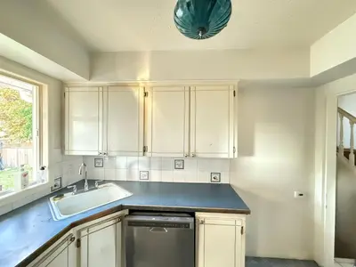 a kitchen with white cabinets and a sink at Downtown Central City Cozy Private 2 Bedroom Basement Suite - Independent Entry in Surrey