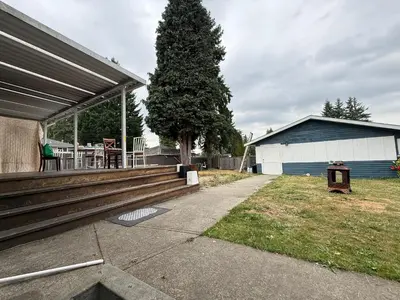 a house with a deck with a table and a tree at Downtown Central City Cozy Private 2 Bedroom Basement Suite - Independent Entry in Surrey