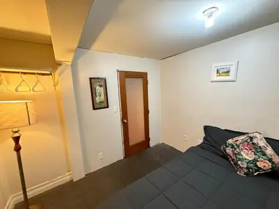 a bedroom with a bed and a lamp and a door at Downtown Central City Cozy Private 2 Bedroom Basement Suite - Independent Entry in Surrey