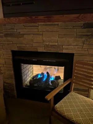 a brick fireplace with a fire in it at Serenity on the Vista's Point at Lac La Nonne in Onoway