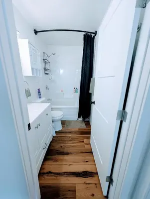 a bathroom with a white toilet and a wooden floor at Serenity on the Vista's Point at Lac La Nonne in Onoway