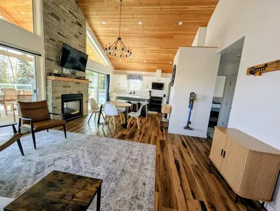 a living room with a fireplace and a dining room at Serenity on the Vista's Point at Lac La Nonne in Onoway
