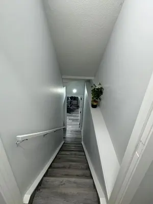 a hallway with white walls and a staircase with a potted plant at Modern comfort just 20 minutes from the airport, with a full kitchen in Edmonton