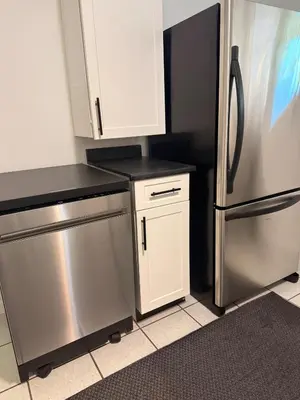 a kitchen with a stainless steel refrigerator and white cabinets at Newly Renovated - Self contained Suite - Sleeps 6 in Vancouver