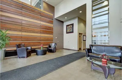 a lobby with leather chairs and a table and a wall at The Spruce Modern 2BR Condo with Pool & Parking in Calgary