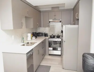 a kitchen with white cabinets and a white refrigerator at Beautiful Basement Suite in Stillwater, West Edmonton in Edmonton