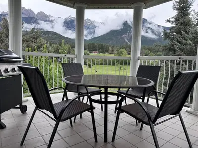 a table and chairs on a porch with a view of mountains at Stunning Mountain View in Fairmont Hot Springs