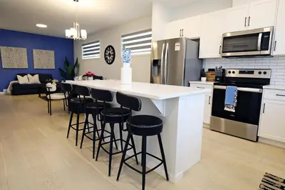 a kitchen with a white counter and bar stools at Seton 4BR Family Home 5 Min to South Campus in Calgary