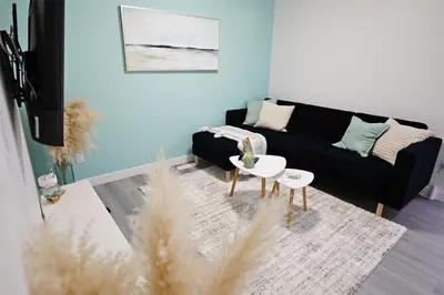a living room with a black couch and a table at Chappelle with AC King Beds Fenced Yard Garage in Edmonton