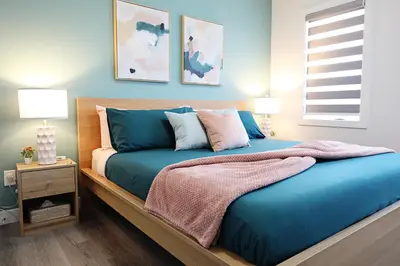 a bedroom with a bed with blue sheets and pillows at Chappelle with AC King Beds Fenced Yard Garage in Edmonton