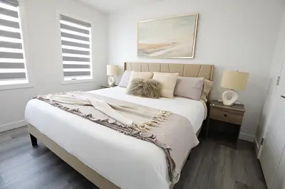 a white bedroom with a large bed and two windows at Chappelle with AC King Beds Fenced Yard Garage in Edmonton