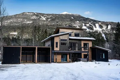 a house in the snow with a mountain in the background at CAPOW House in Revelstoke