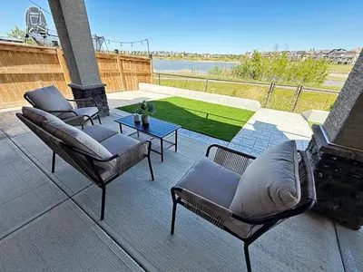 a patio with two chairs and a table with a view at Mahogany Lakefront 2BR Walkout Trails And Privacy in Calgary