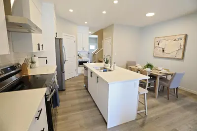 a kitchen with white cabinets and a table and a dining room at Edgemont Getaway King Bed Garage WEM And DisneyPlus in Edmonton