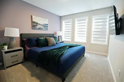 a bedroom with a bed with blue sheets and pillows at Edgemont Getaway King Bed Garage WEM And DisneyPlus in Edmonton