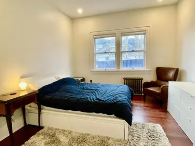 a bedroom with a bed and a chair and a window at The Algonquin Residence in Prince Rupert