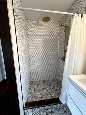 a bathroom with a shower with a tiled floor at The Algonquin Residence in Prince Rupert