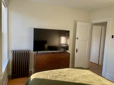 a bedroom with a dresser and a flat screen tv at The Golden Sky Sanctuary at the Algonquin Residence in Prince Rupert