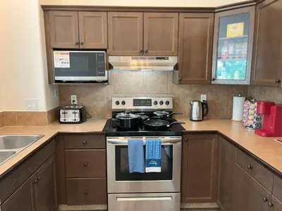 a kitchen with a stove and a microwave at 3 Adjacent 4-bed Homes - Park Views, Fully Stocked in Grande Prairie