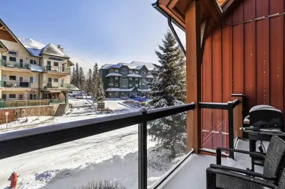 a balcony with a snow covered street and houses at Mountain Escape 2BR Hot tub and Pool Near Banff in Canmore