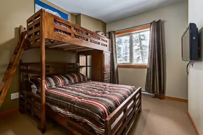 a bedroom with a bunk bed and a television at Spacious Getaway near Banff with Heated Pool in Canmore
