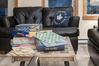 a pile of books on a coffee table in front of a couch at 3BR Rockies Condo Heated Pool and Hot Tub in Canmore