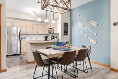 a kitchen with a table with chairs and a refrigerator at 3BR Rockies Condo Heated Pool and Hot Tub in Canmore