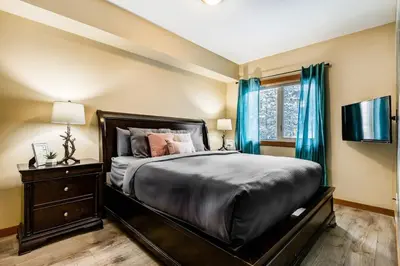a bedroom with a large bed with blue curtains at 3BR Rockies Condo Heated Pool and Hot Tub in Canmore