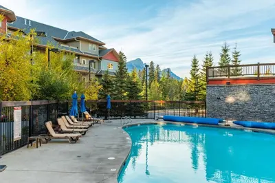 a swimming pool with lounge chairs and a resort at 3BR Rockies Condo Heated Pool and Hot Tub in Canmore