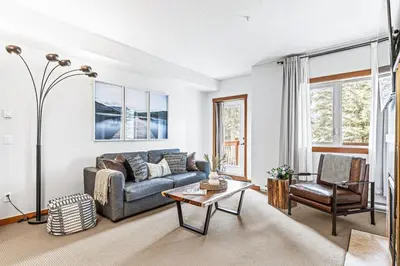 a living room with a couch and a table at Chic 1BR City Nest Heated Parking and Hot Tub and Pool in Canmore
